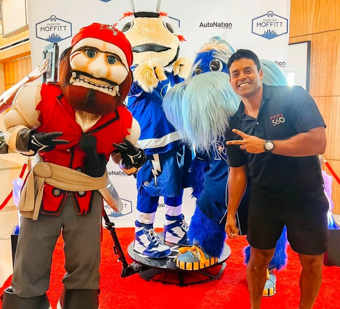 A man is standing next to a mascot on a red carpet.