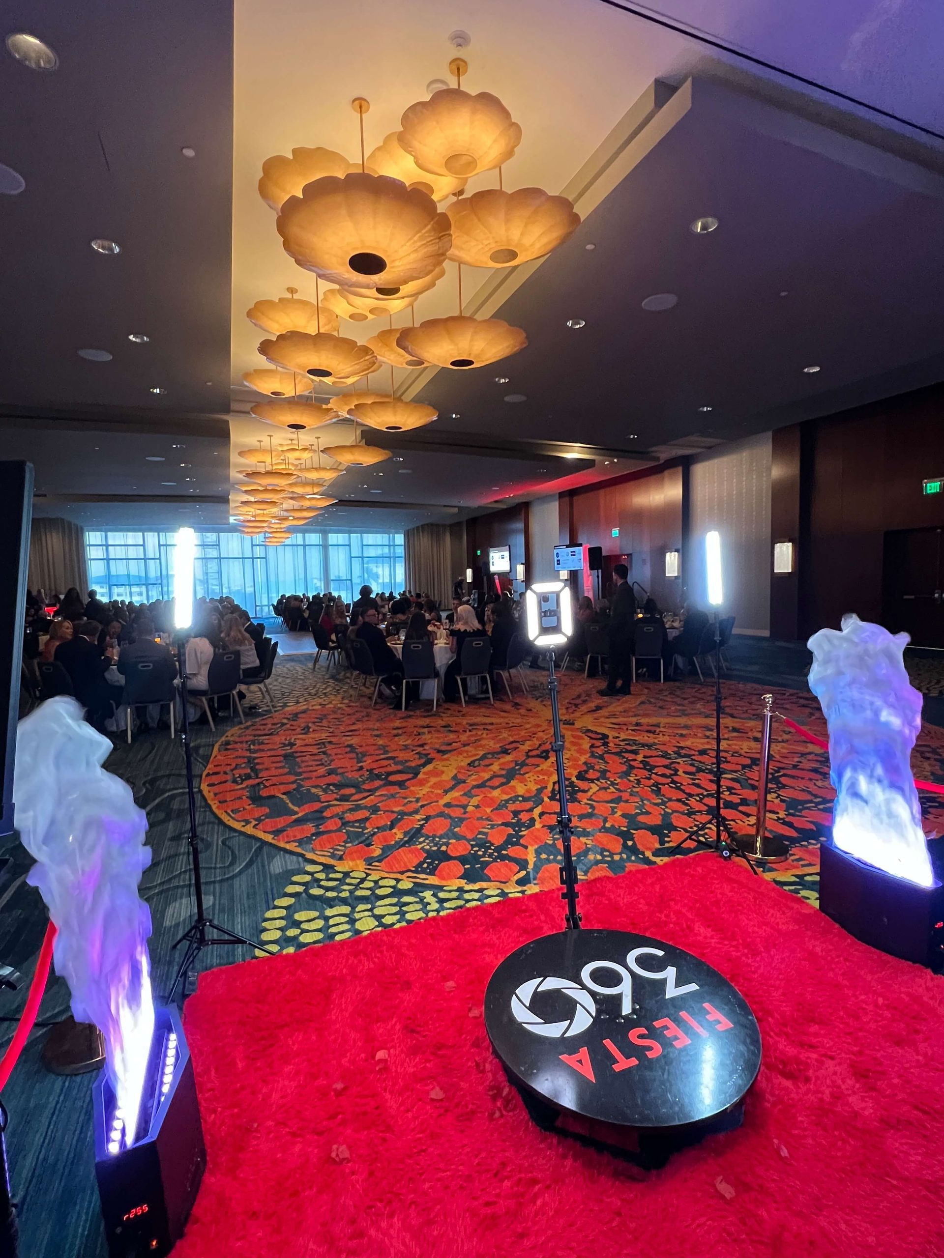 A photo booth is sitting on a red carpet in a large room.