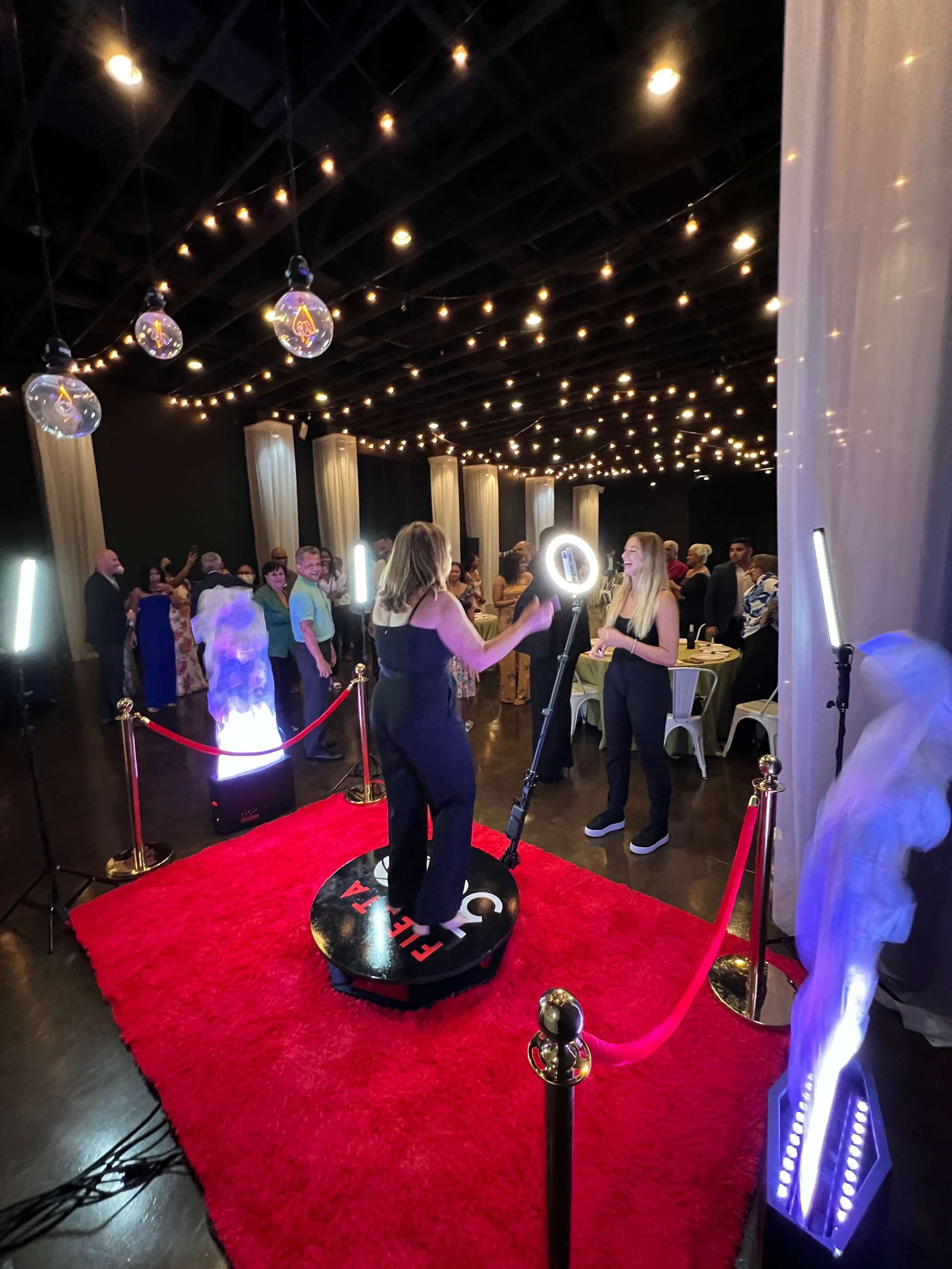 A woman is standing on a red carpet in front of a photo booth.