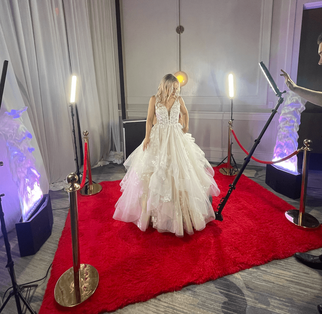 A woman in a wedding dress is standing on a red carpet.