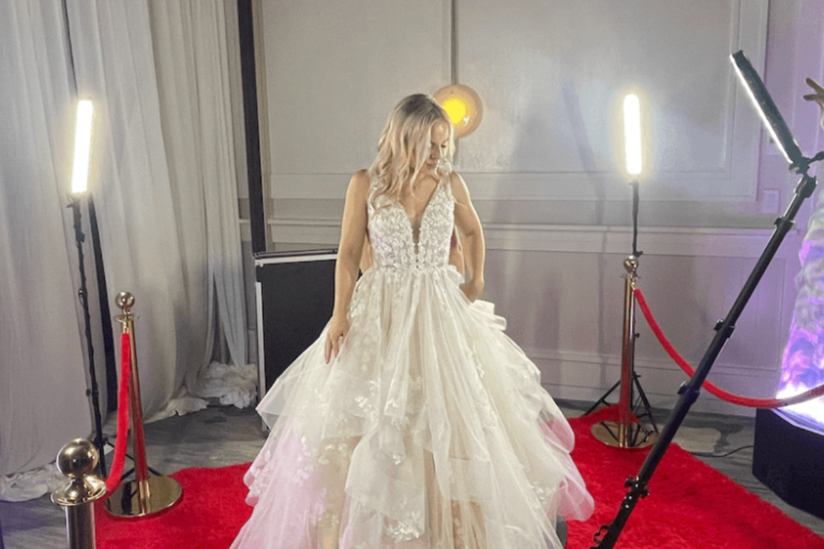 A woman in a wedding dress is standing on a red carpet.