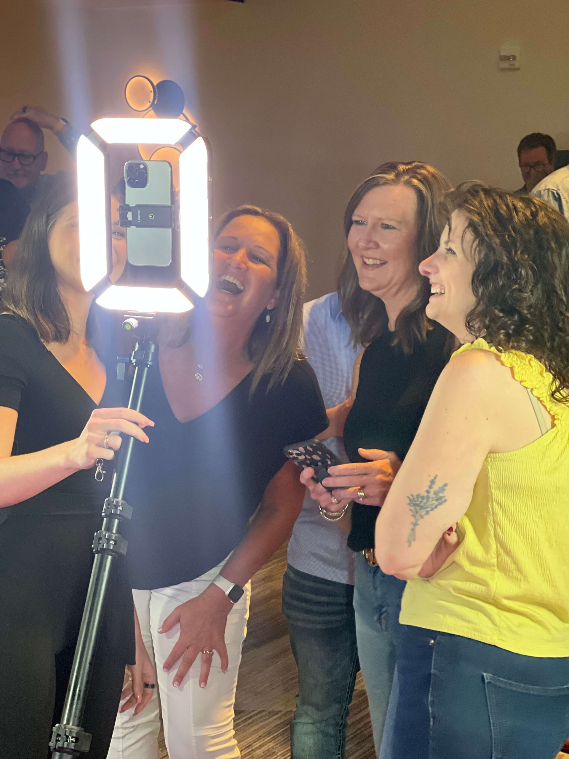 A group of women are posing for a picture with a light on a tripod.