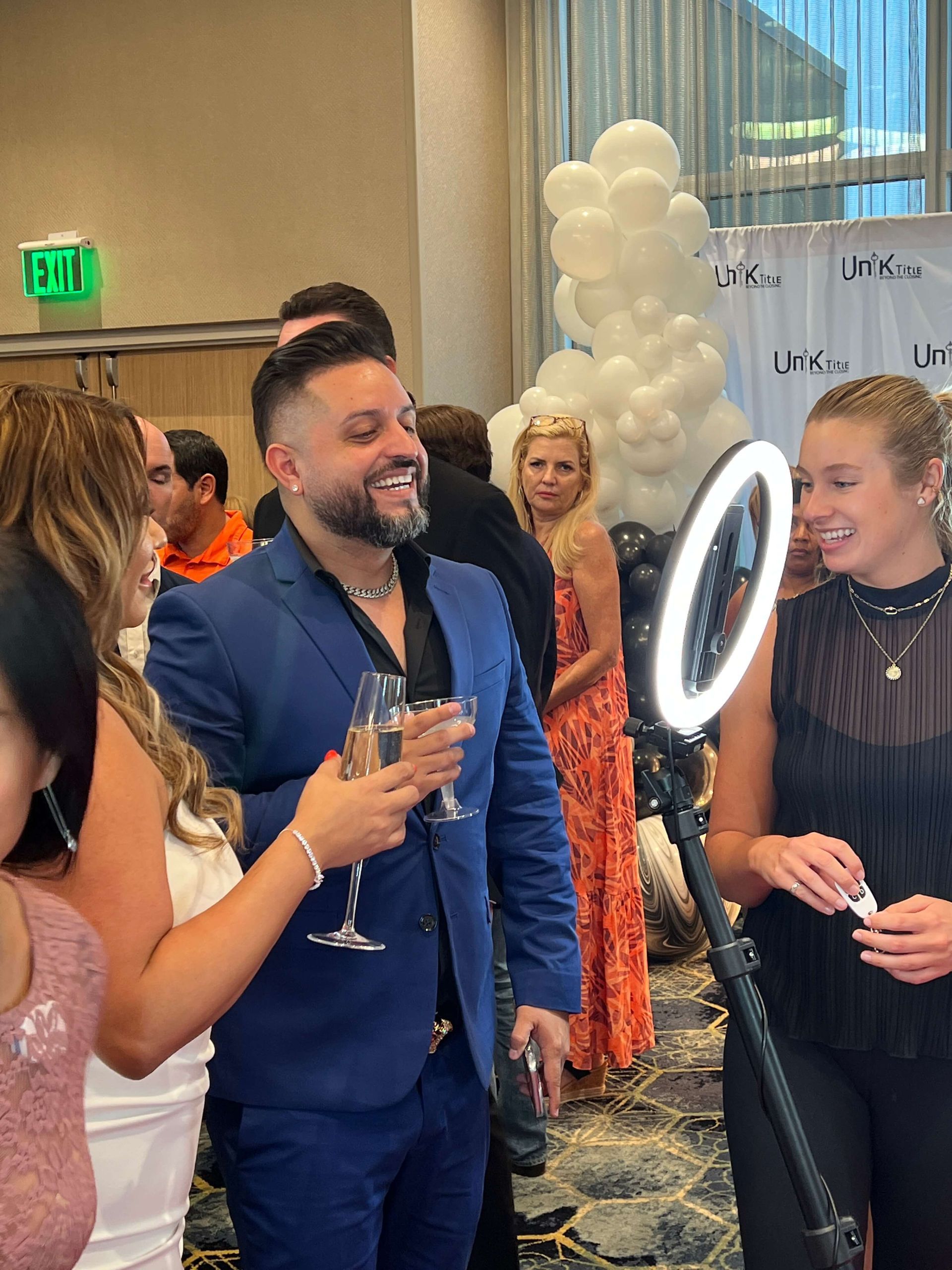 A group of people are standing around a ring light in a room.