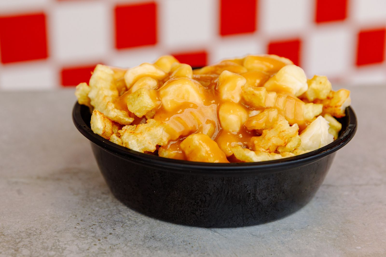 A bowl of poutine is sitting on a table.