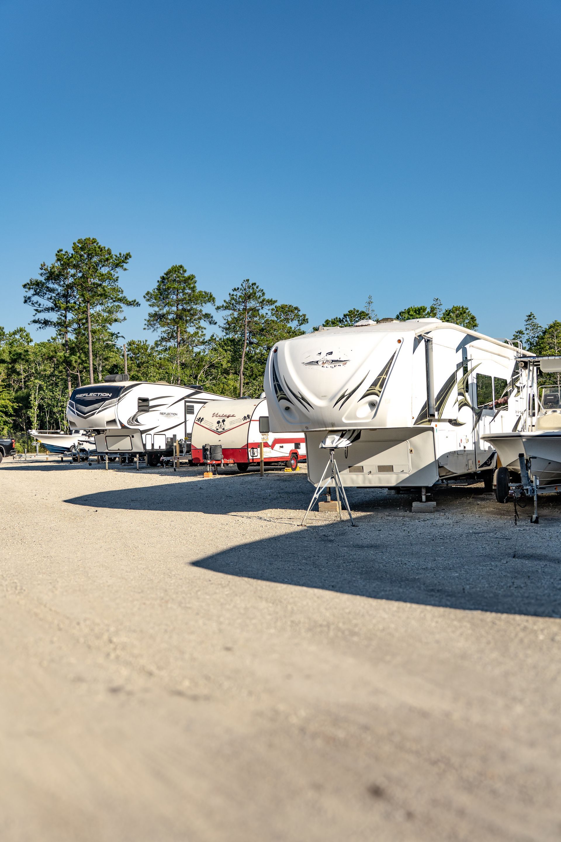 A white rv is parked in a gravel lot