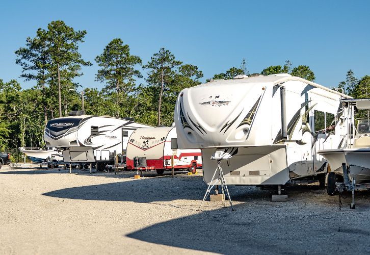 A white rv is parked in a gravel lot