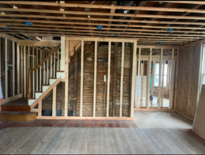 Interior of a house under construction; wooden framing, concrete floor, empty room, natural light.