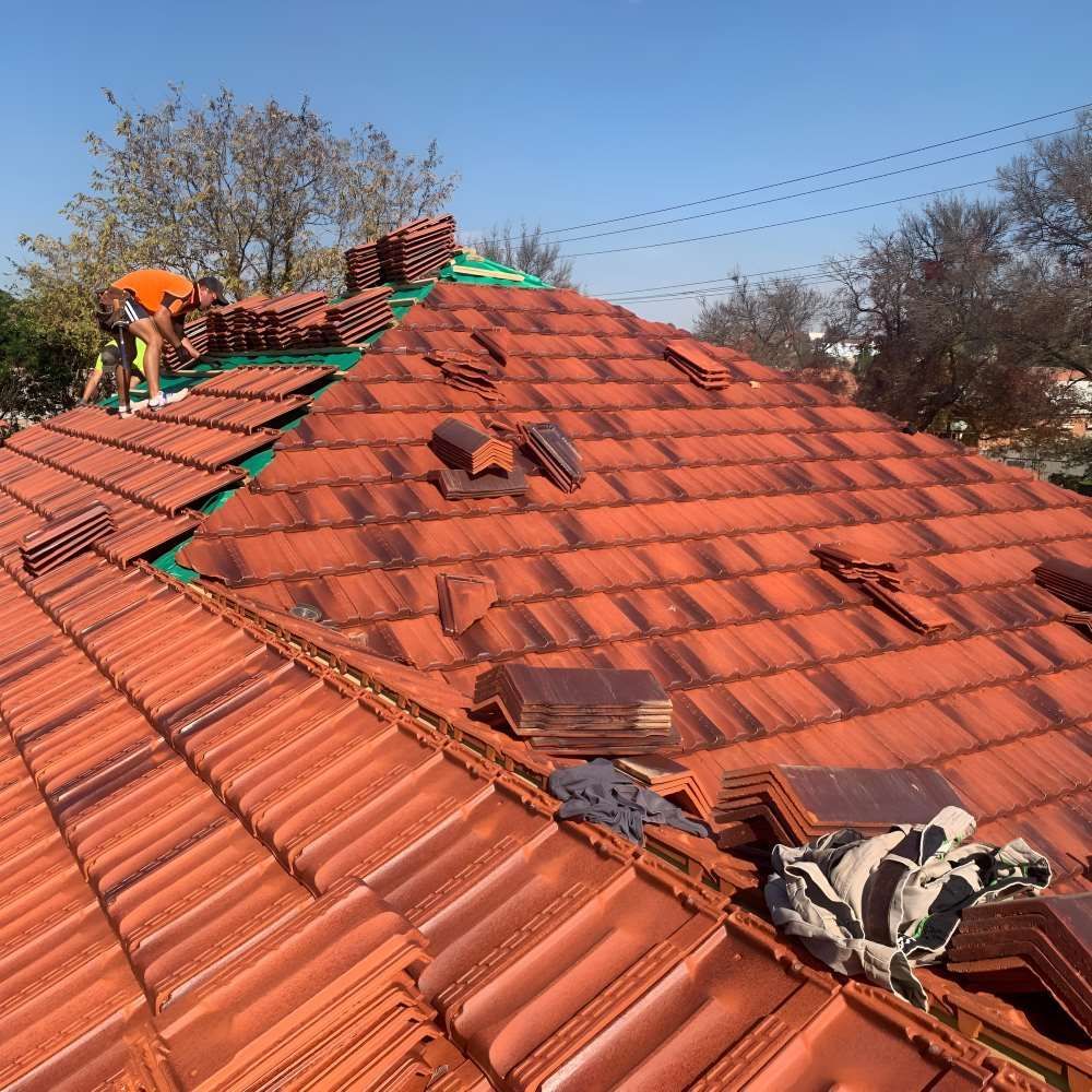 A Man Is Working On The Roof Of A House — Lance Ward Roof Tiling in Orange, NSW