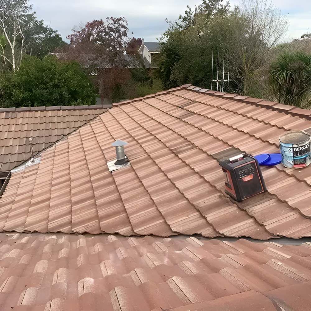 A Roof With A Bucket Of Paint Sitting On Top Of It — Lance Ward Roof Tiling in Orange, NSW