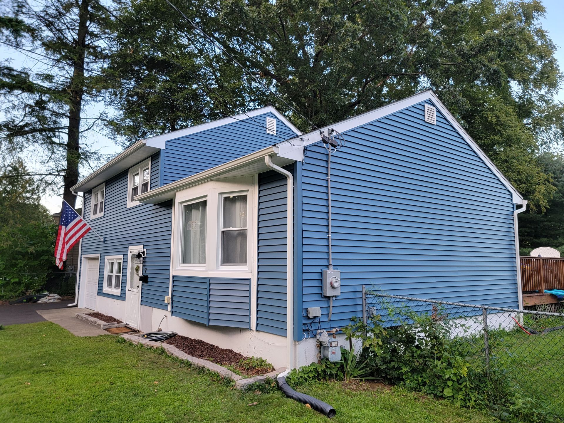 A blue and white house with an american flag on the side of it.