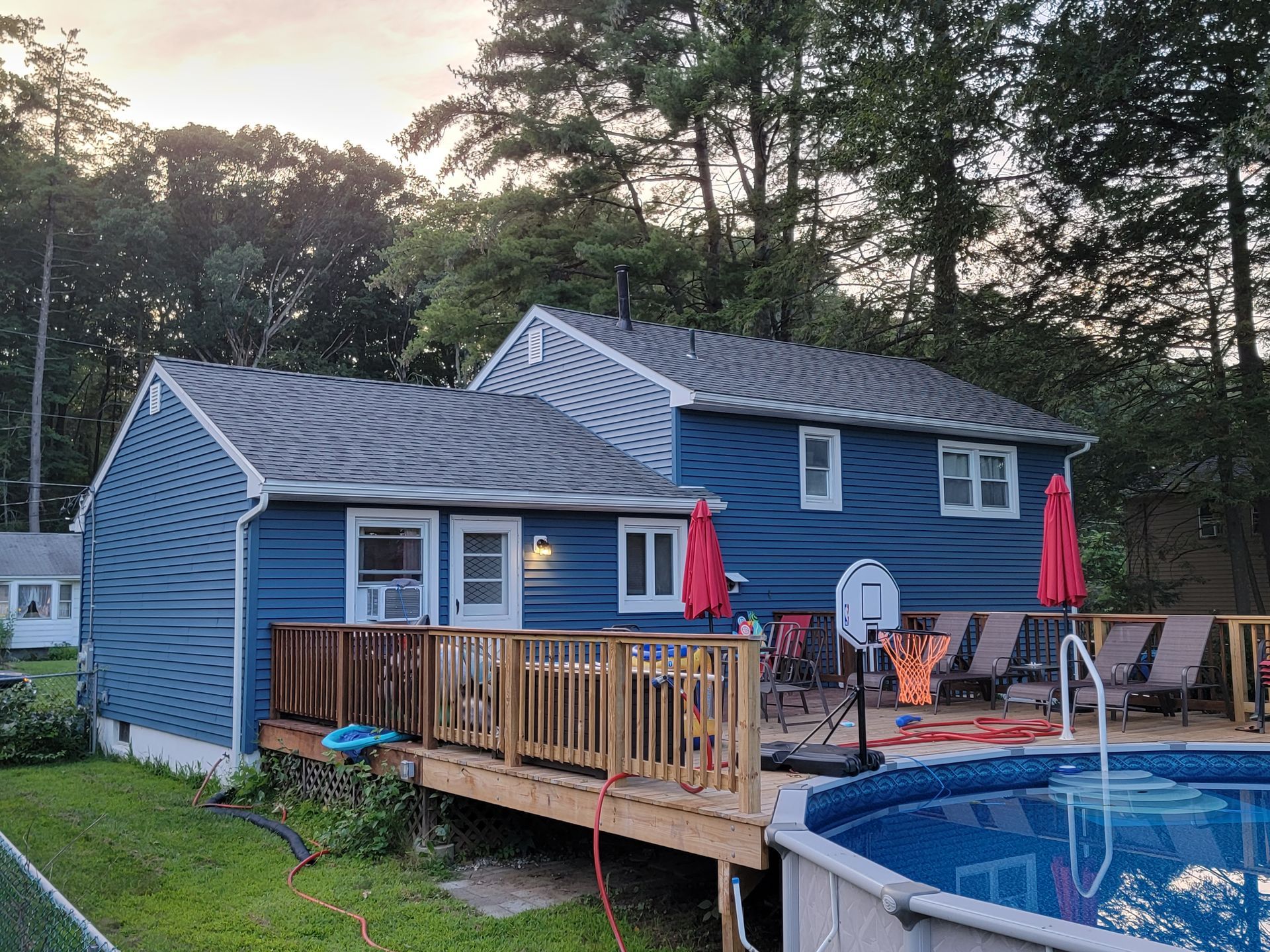 A blue house with a deck and a pool in front of it.