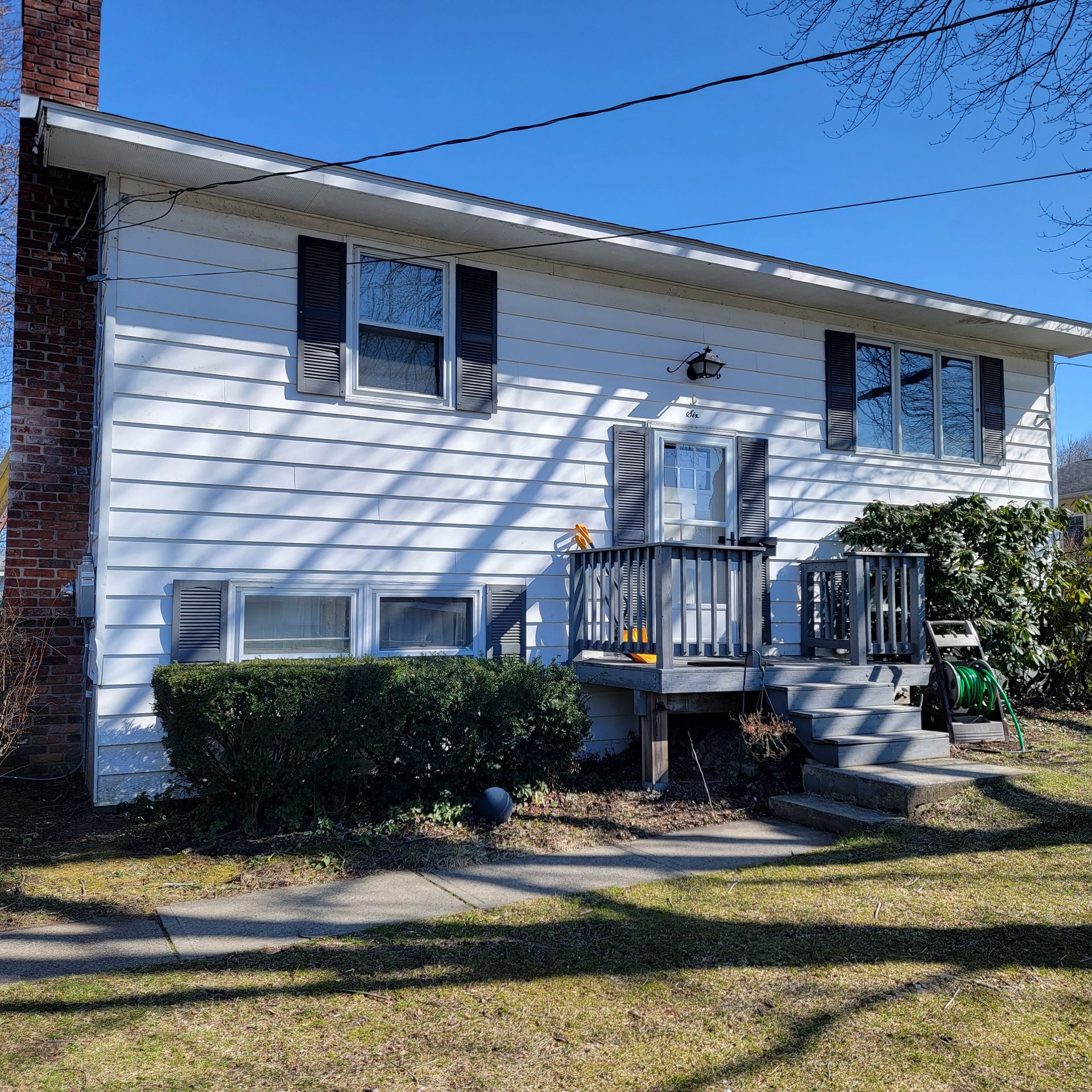 A white house with black shutters and a deck