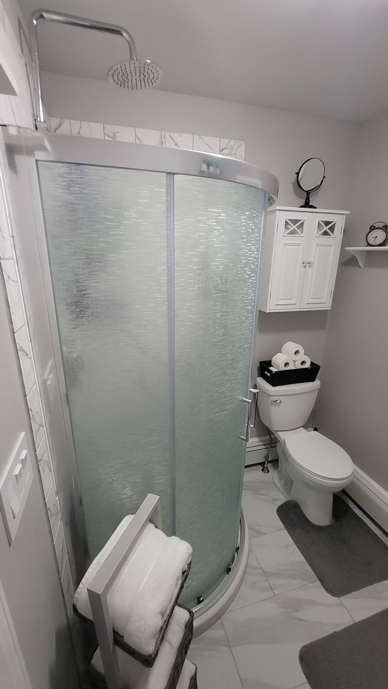 A bathroom with a toilet , shower , and mirror.