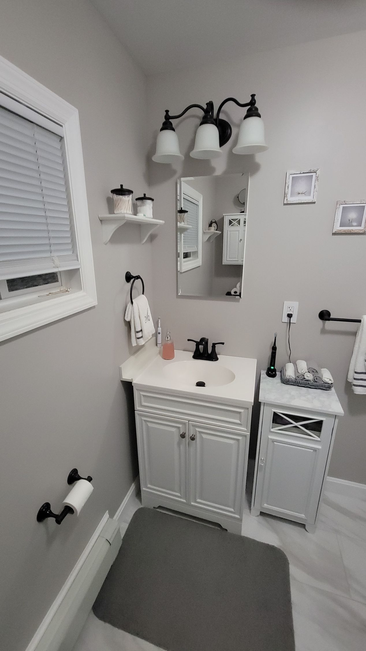 A bathroom with a sink , mirror , and window.