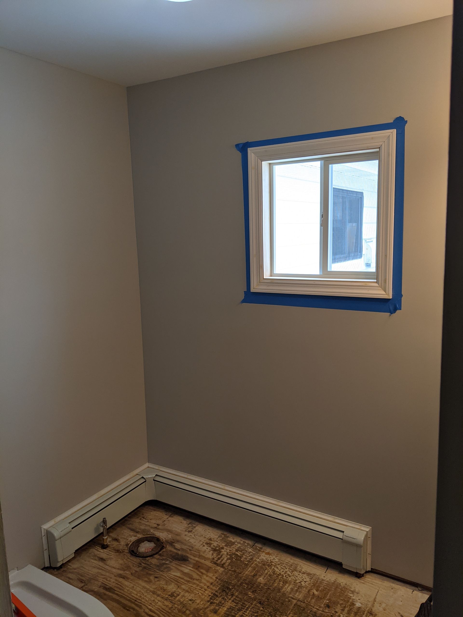 A room with a window and a heater on the floor