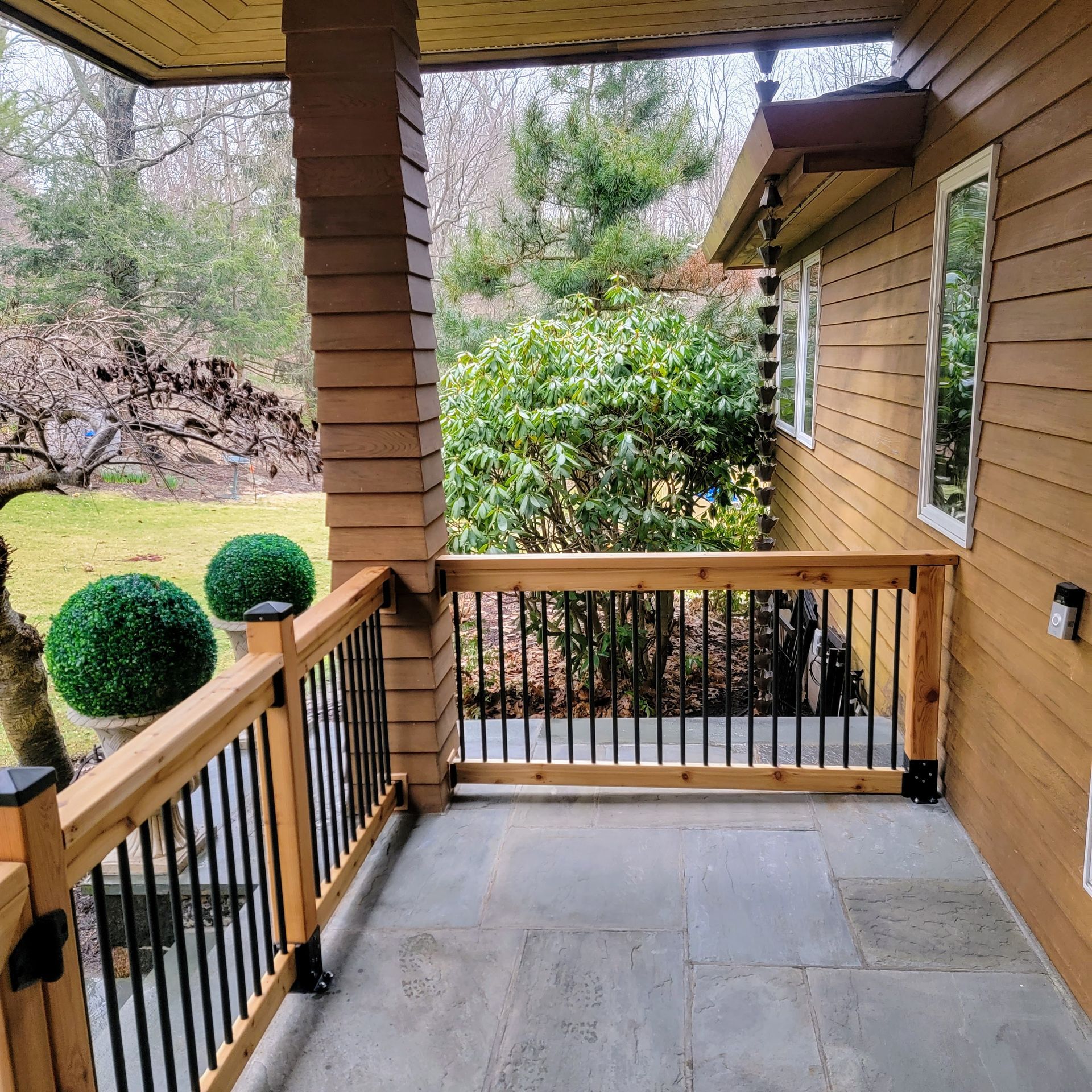 A porch with a wooden railing and trees in the background