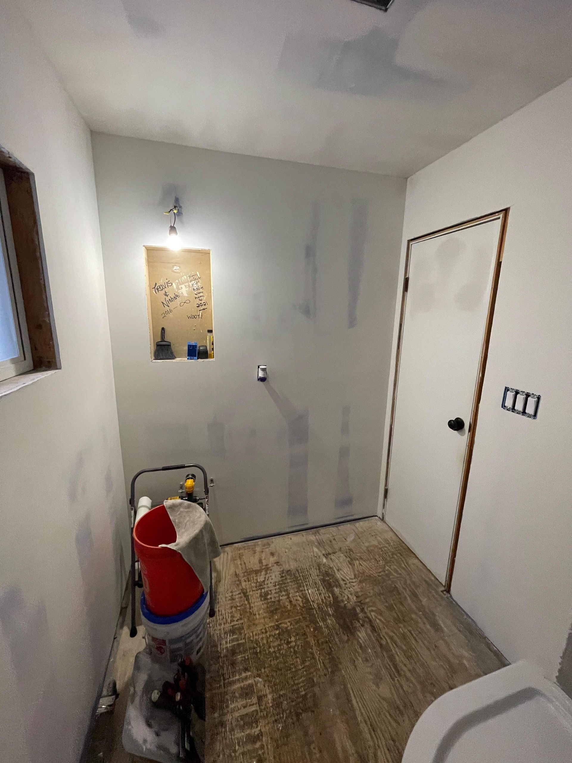 A bathroom under construction with a toilet , sink , and door.