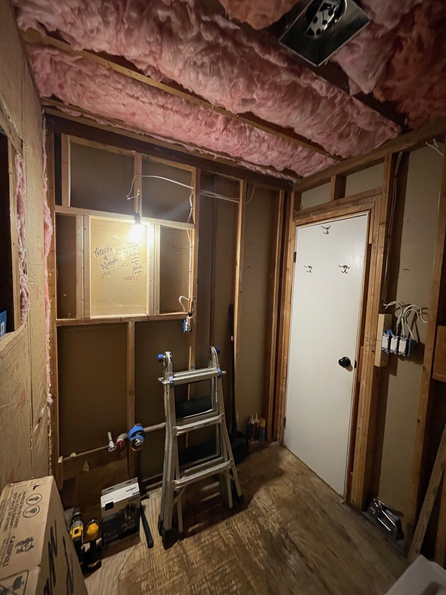 A room with pink insulation and a ladder in it.