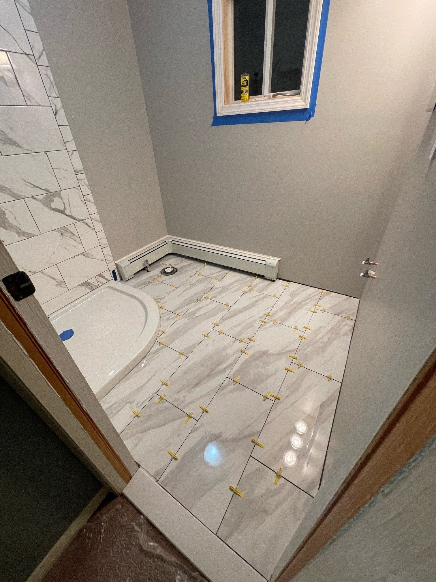 A bathroom with a tiled floor and a window.
