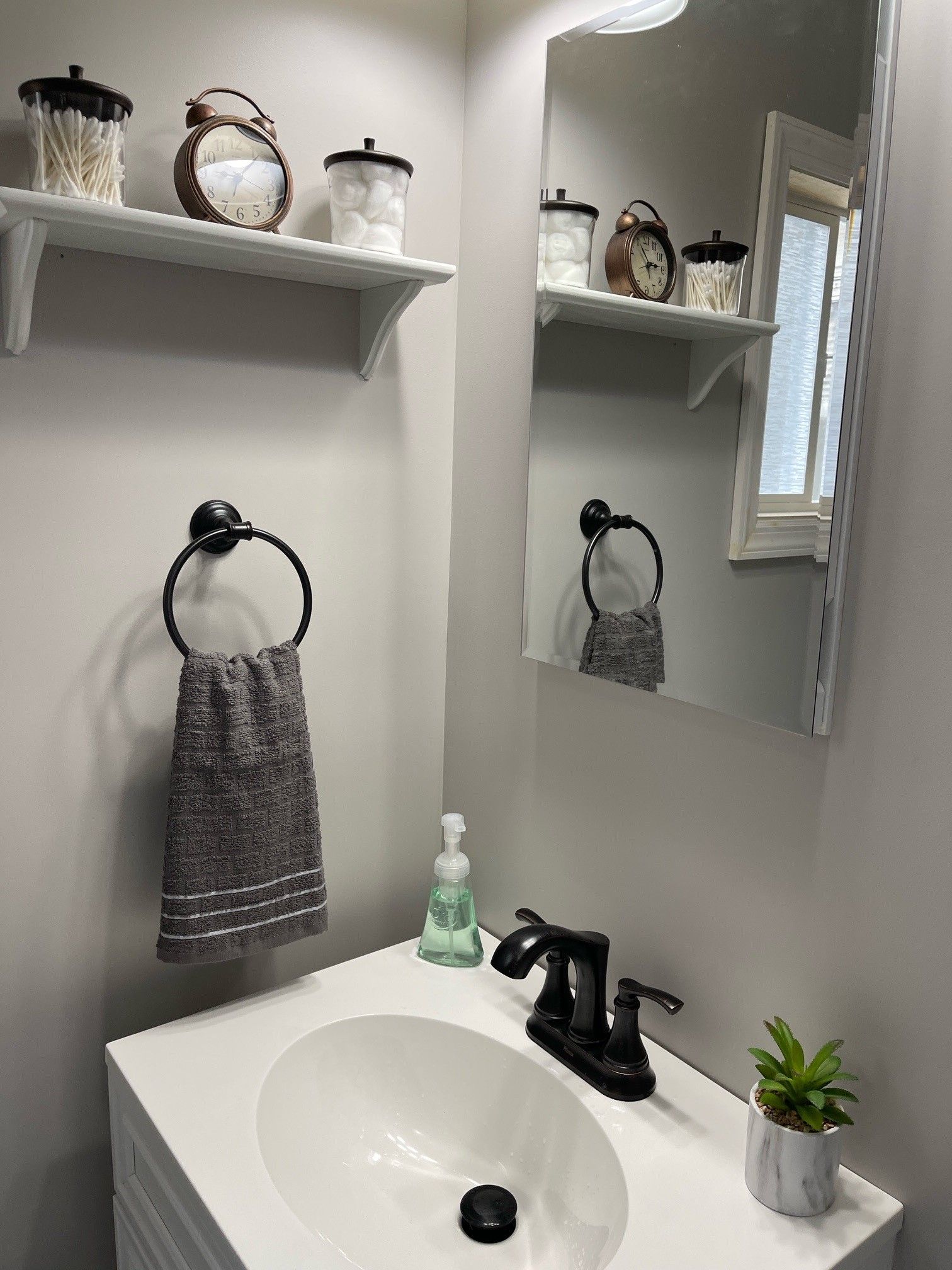 A bathroom with a sink , mirror and shelf.