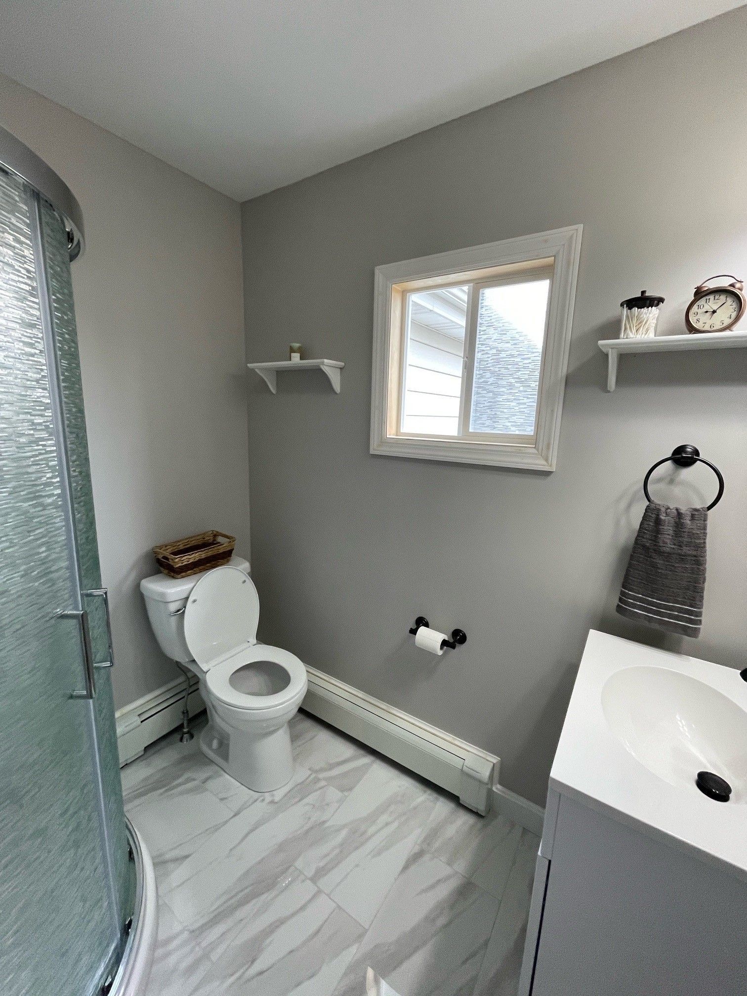 A bathroom with a toilet , sink , shower and window.