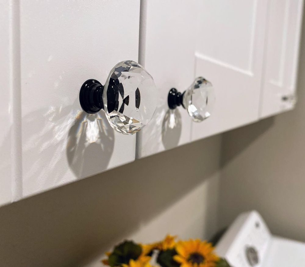 A laundry room with white cabinets and clear glass knobs.