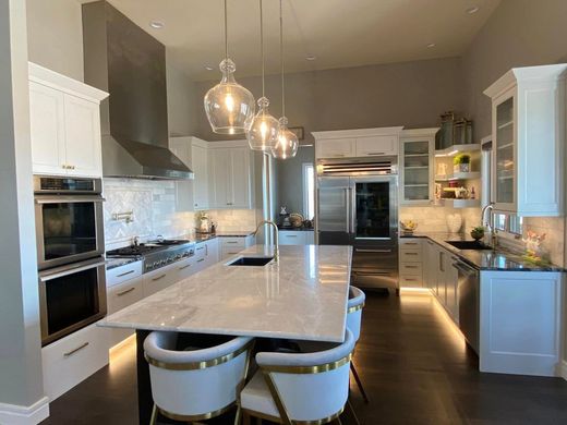 A kitchen with white cabinets and stainless steel appliances and a large island.