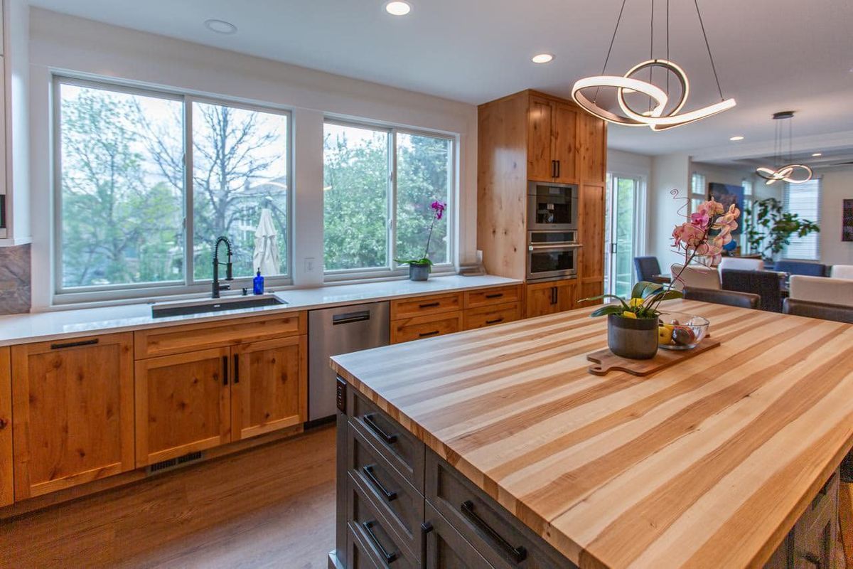 A kitchen with wooden cabinets and a large wooden island.