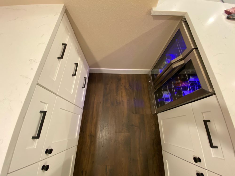A kitchen with white cabinets and a wine cooler