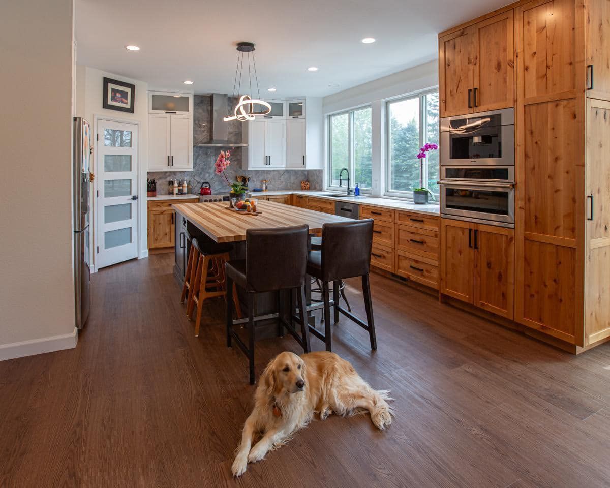 A dog is laying on the floor in a kitchen next to a table.