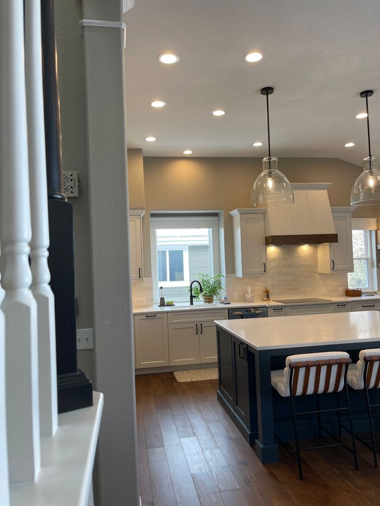 A kitchen with white cabinets , a large island , a sink and a window.