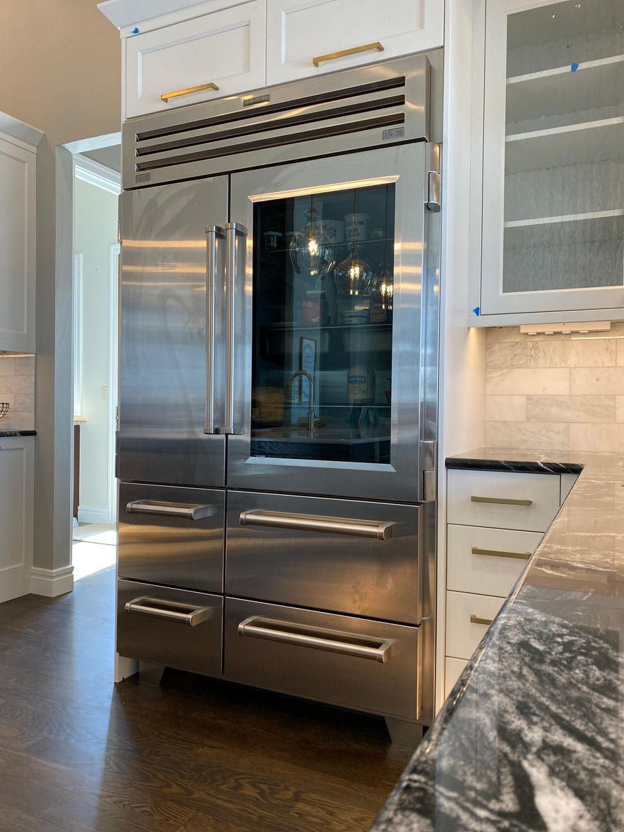 A stainless steel refrigerator with a glass door is in a kitchen.