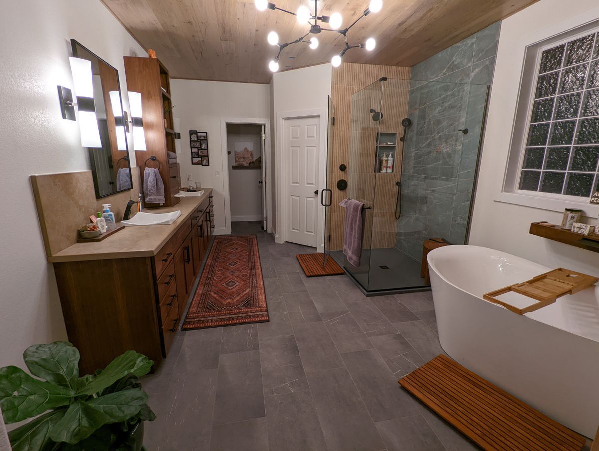 A bathroom with a tub , sinks , mirrors and a walk in shower.
