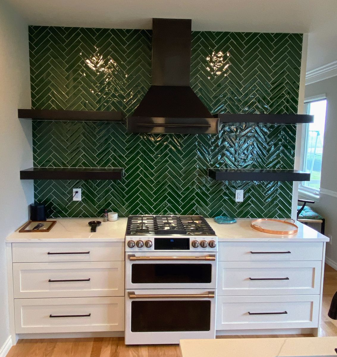 A kitchen with green tiles and white cabinets