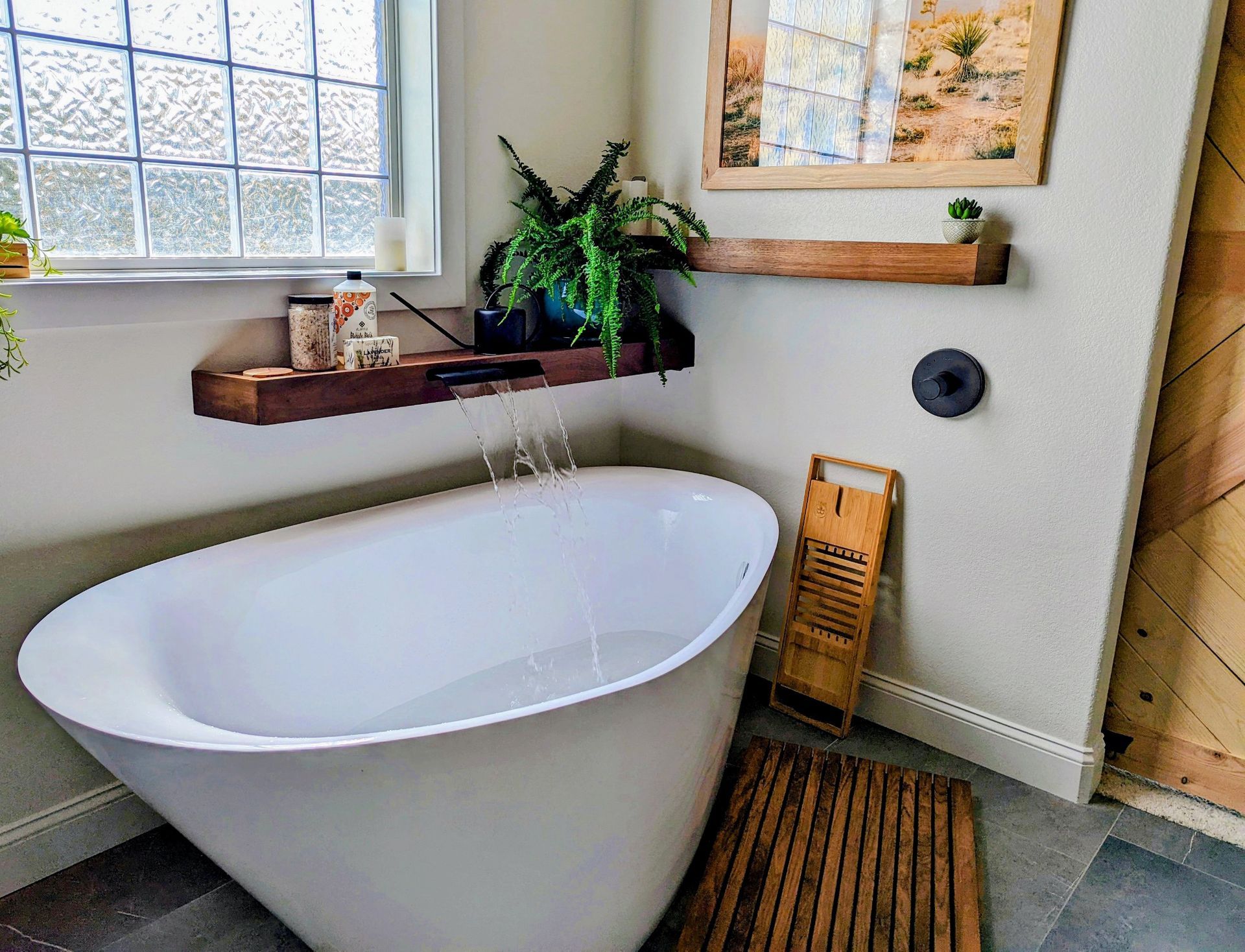 A bathroom with a bathtub and a wooden shelf.