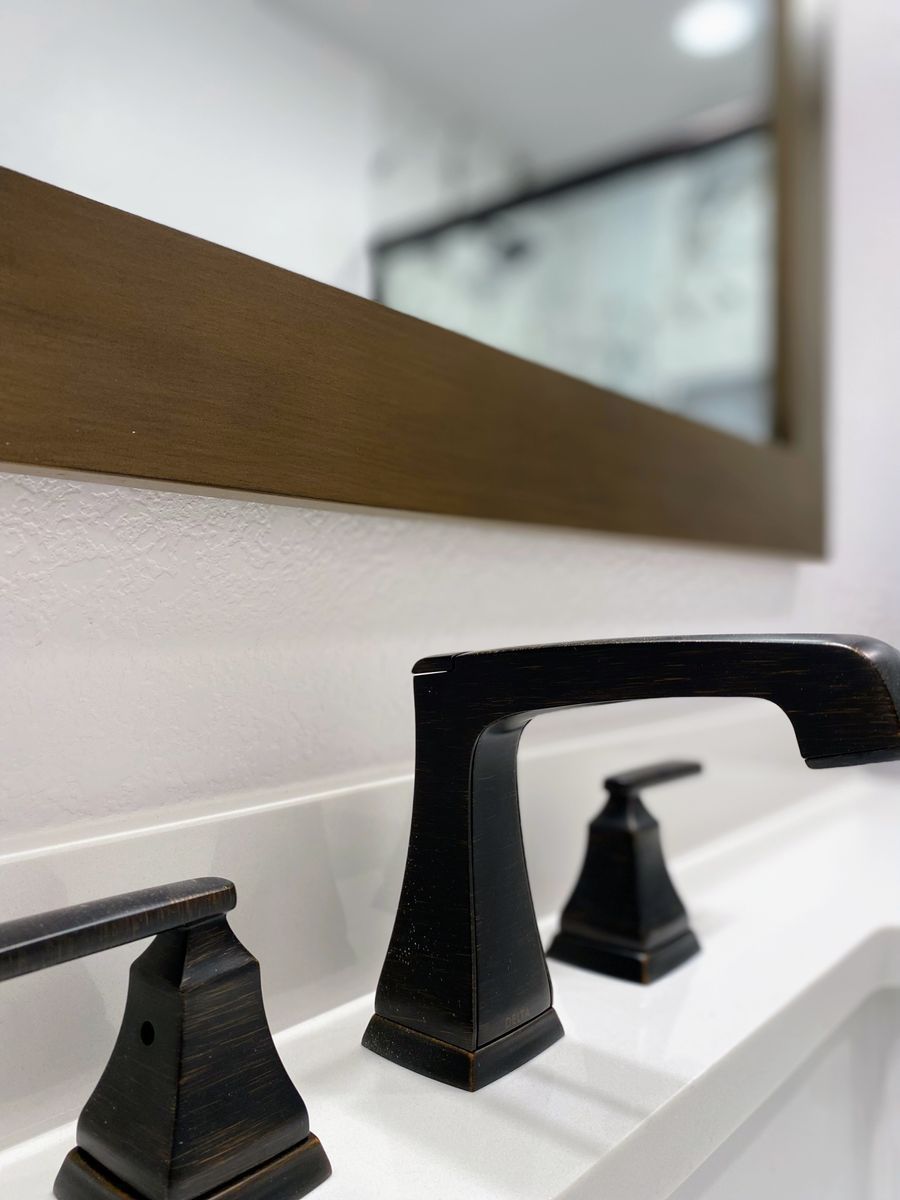 A bathroom sink with black faucets and a mirror