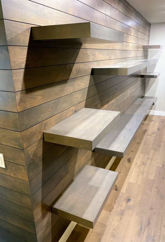 A row of shelves against a wooden wall in a room.