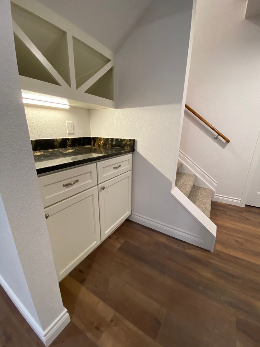 A kitchen with a sink , cabinets , and stairs.