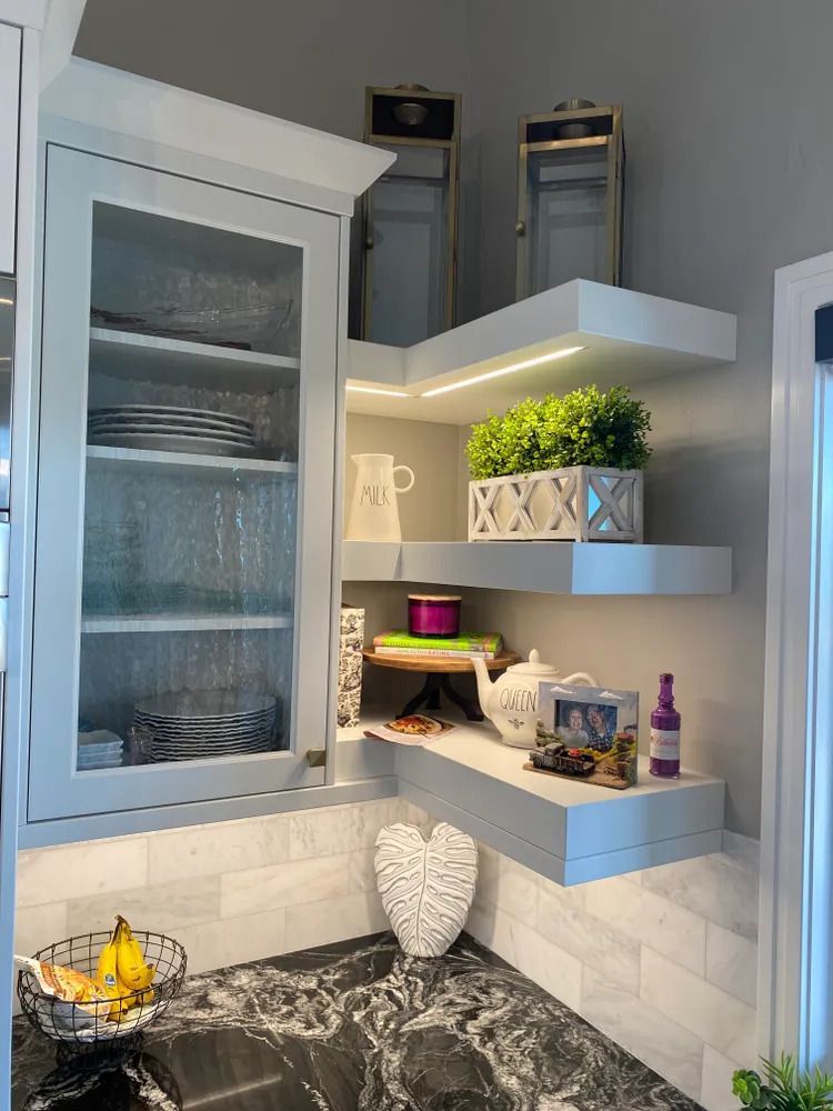 A kitchen with a sink , shelves , and cabinets.