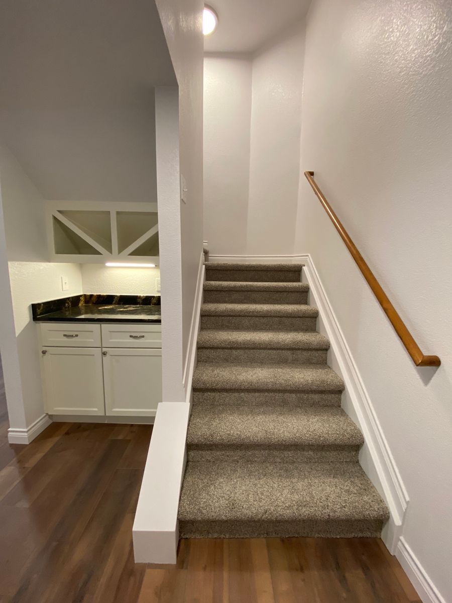 A set of stairs leading up to a kitchen with a wooden railing.