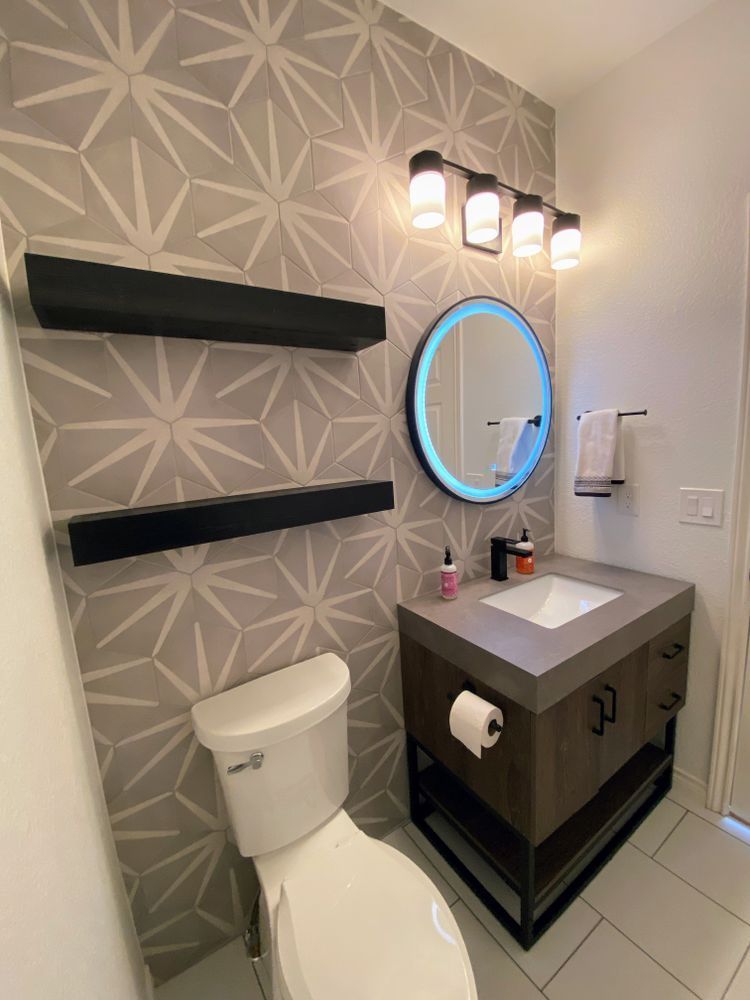 A bathroom with a toilet , sink , mirror and shelves.