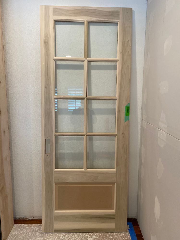 A wooden door with glass is sitting in a room.