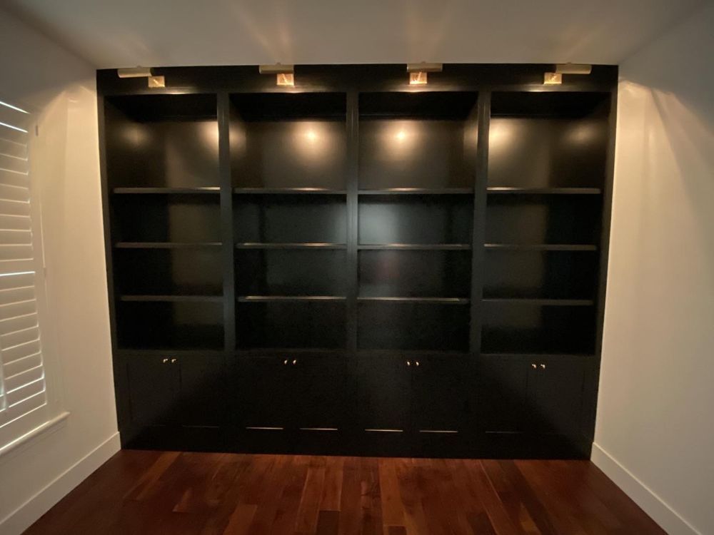 A room with black shelves and shutters on the windows