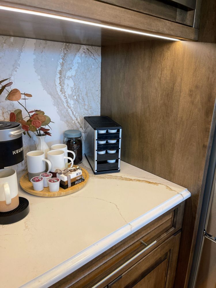 A kitchen counter with a coffee maker and cups on it.