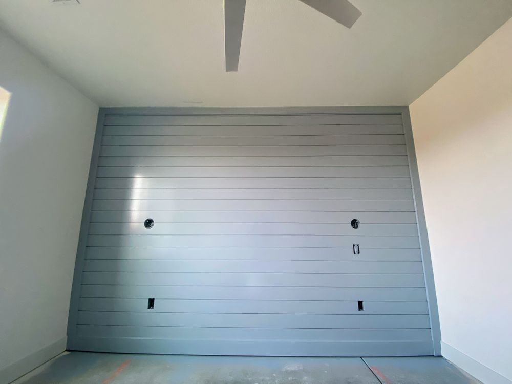 A room with a ceiling fan and a gray wall.