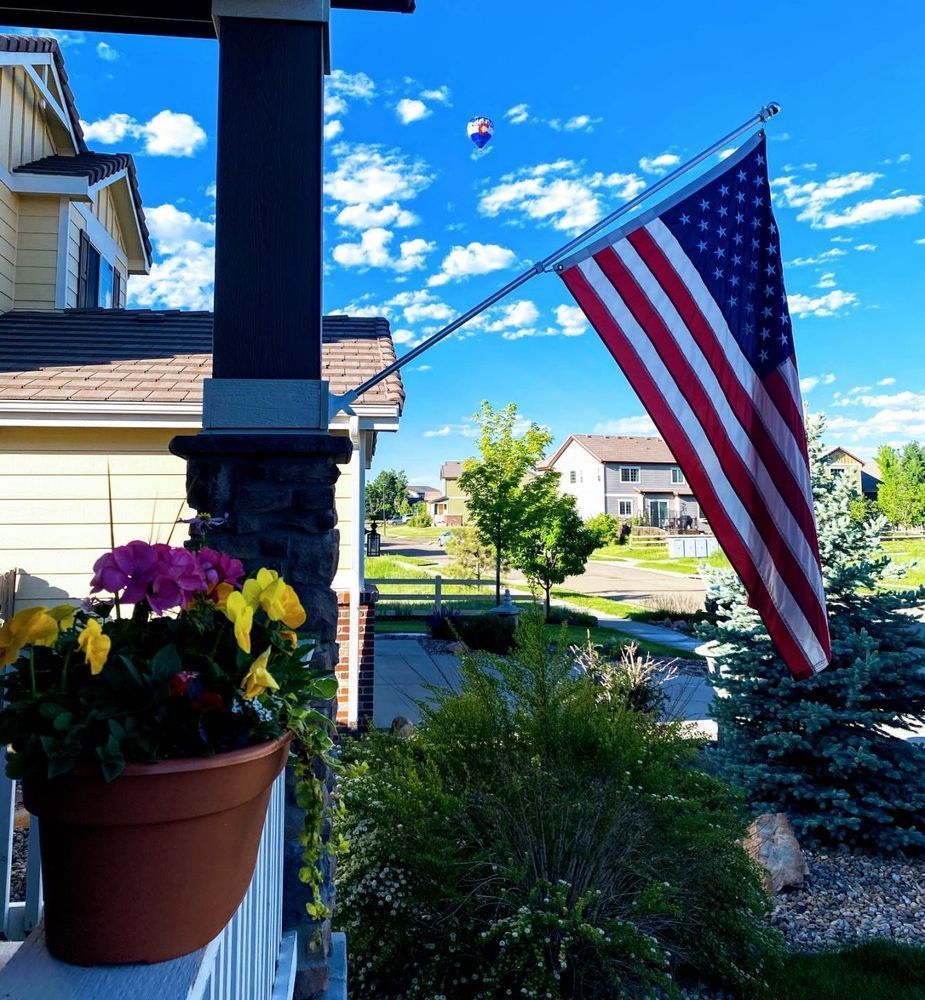 A pot of flowers sits on a porch next to an american flag