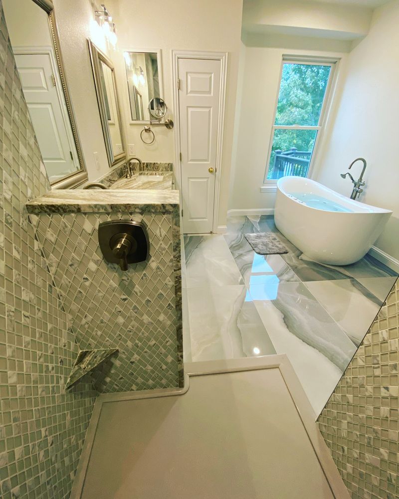 A bathroom with a tub , sink , mirror and window.