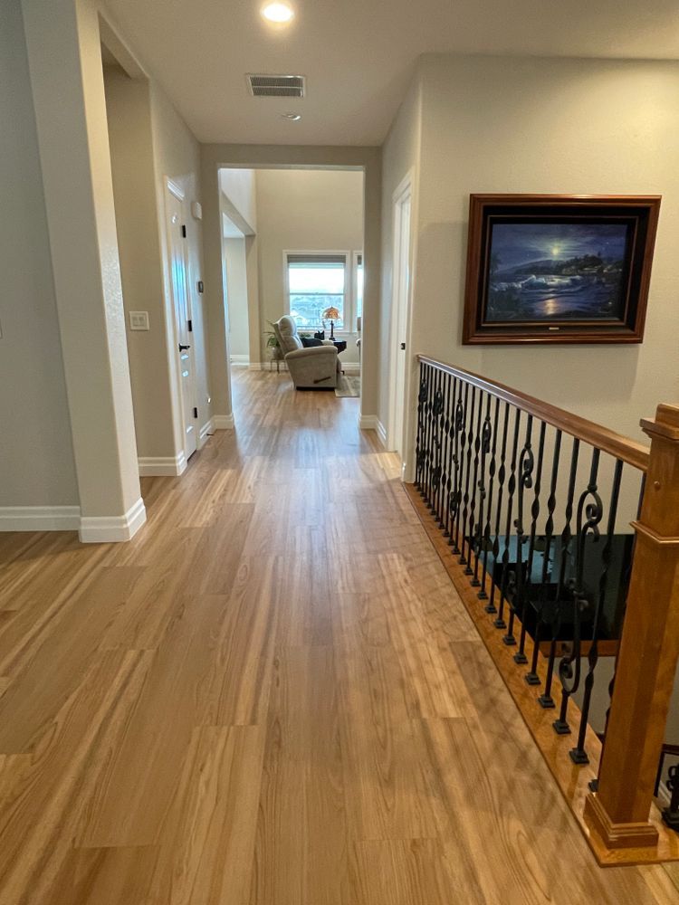 A hallway with hardwood floors and a staircase in a house.