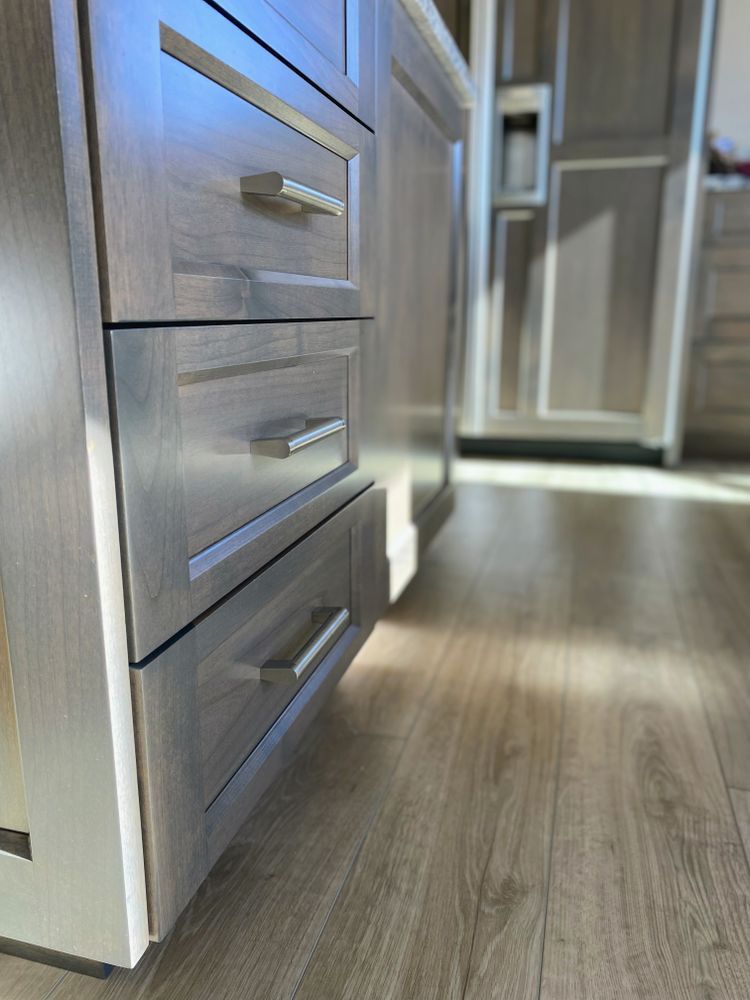 A kitchen with stainless steel drawers and a wooden floor.