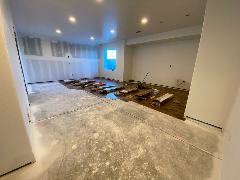A large room with a wooden floor and white walls is being remodeled.
